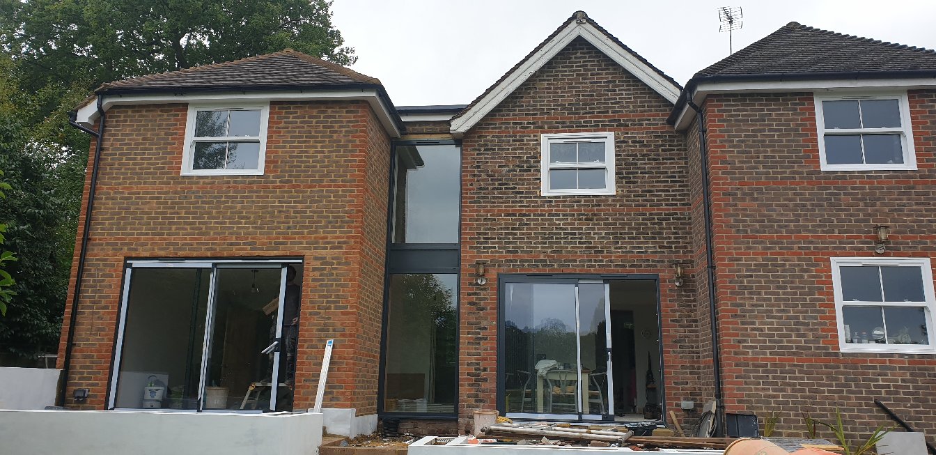 Two storey rear house extension in East Sussex with matched red brickwork and full width aluminium bifold doors built by Two Build