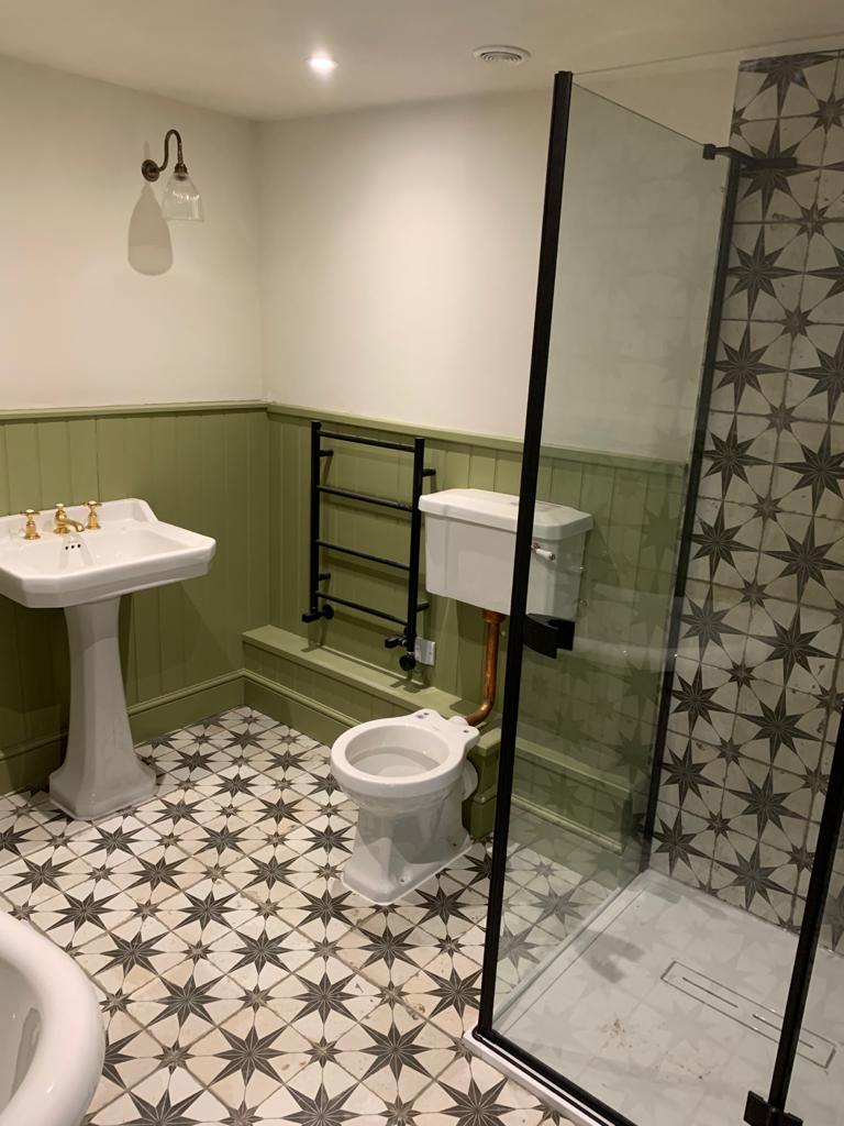 New en suite shower room with walk in glass screen, pedestal basin and brass fittings in a renovated East Sussex cottage