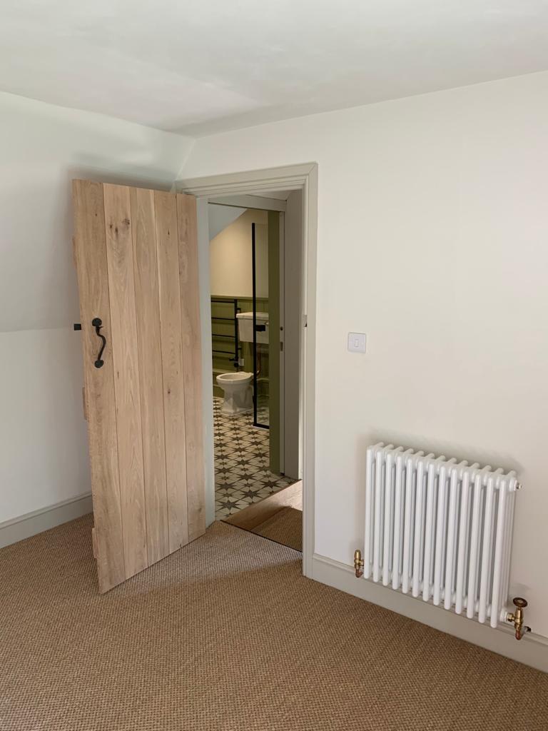 Solid oak plank door with traditional black ironmongery hung by Two Build during a period cottage renovation
