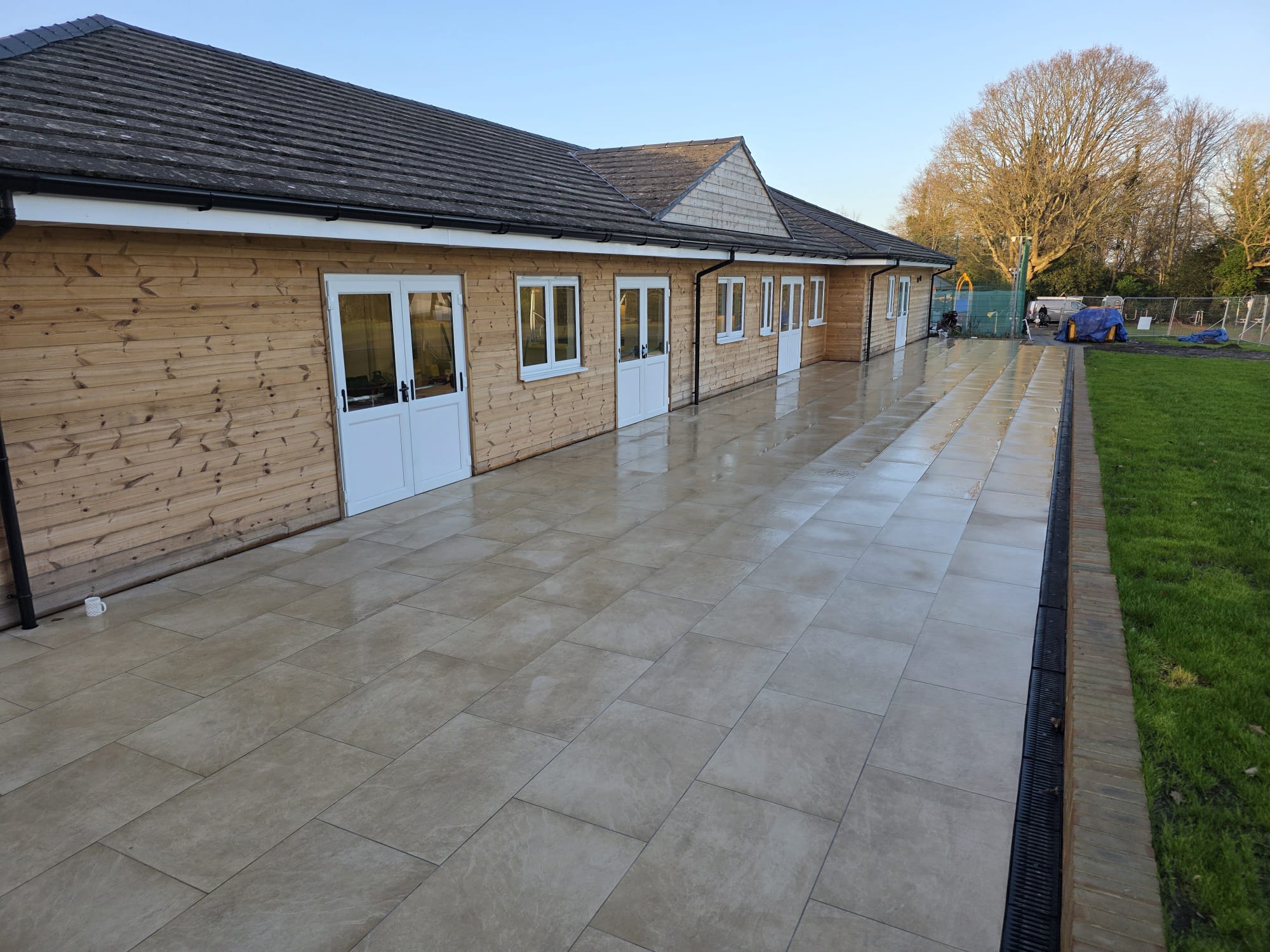 The same sports clubhouse after renovation by Two Build, re-clad in natural timber with a large porcelain tiled terrace and channel drainage